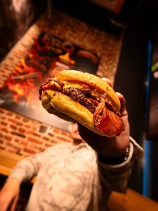 Burger au bacon Tonton Chami tenu à bout de bras