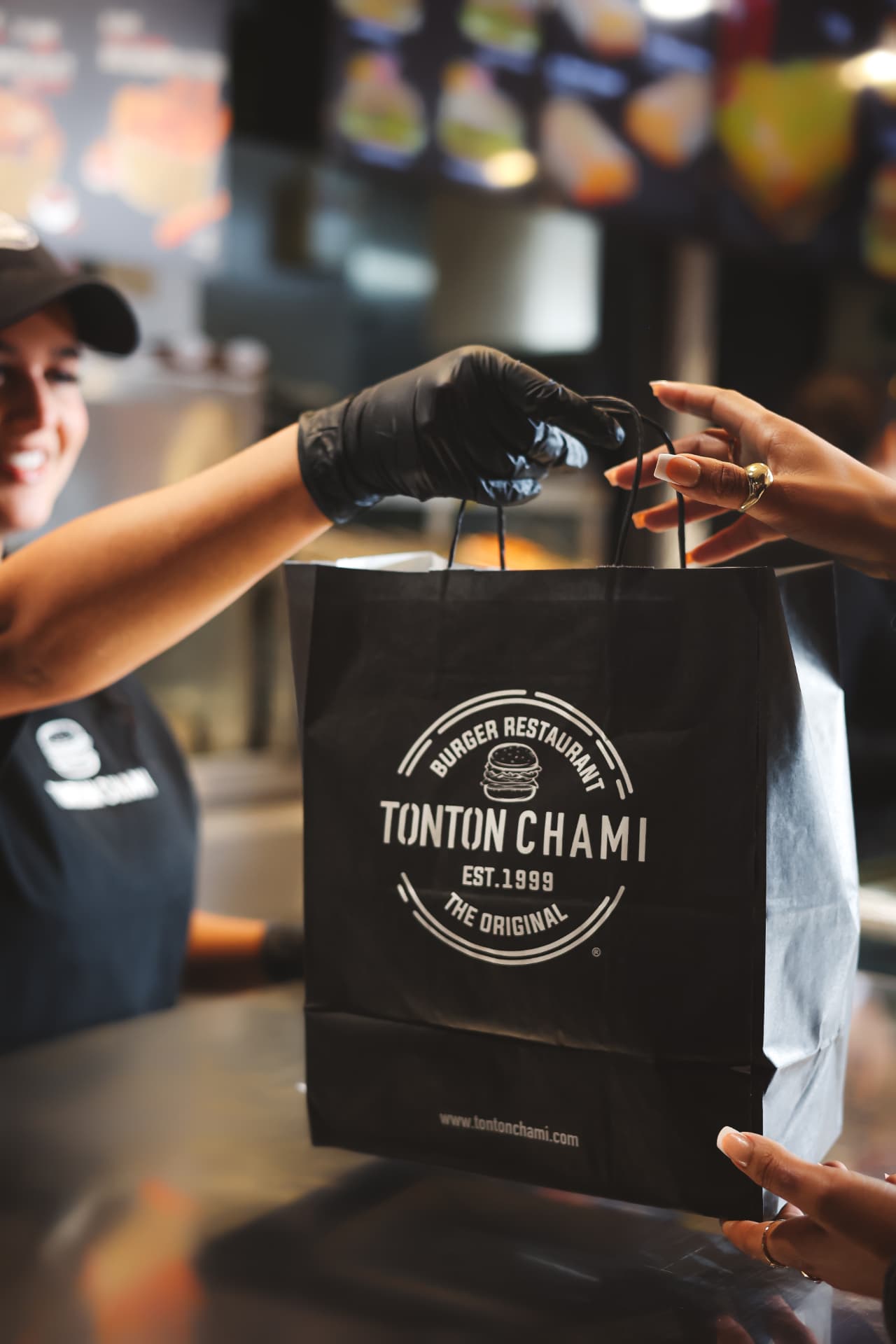 Remise d'un sac Tonton Chami entre deux personnes, logo visible